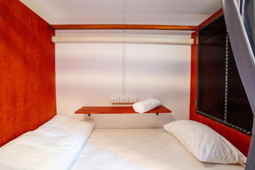 a small bedroom with two beds and a shelf at Coasta Wings Hostel in Nathon Bay