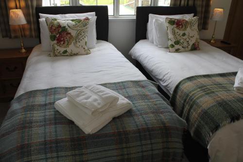 two twin beds with towels on them in a room at Three Horseshoes Country Inn in Barry