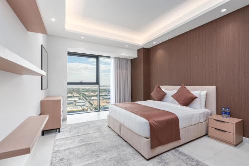 a bedroom with a large bed and a large window at Samaya Holiday Homes - Cloud Stylish Suites with Balcony in Dubai