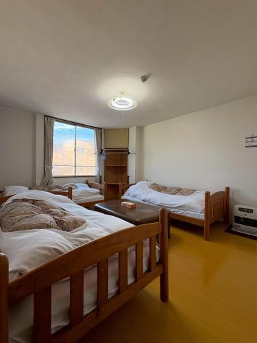 a room with three beds and a window at 駅本ビル民宿4階 in Yuzawa