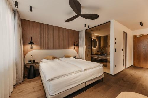 a bedroom with a large bed with a ceiling fan at Hotel Hell in Ortisei