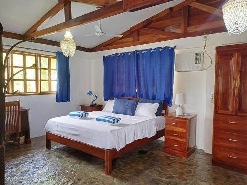 a bedroom with a large bed with blue curtains at Rainbow Bay Beach & Dive Resort in Siquijor