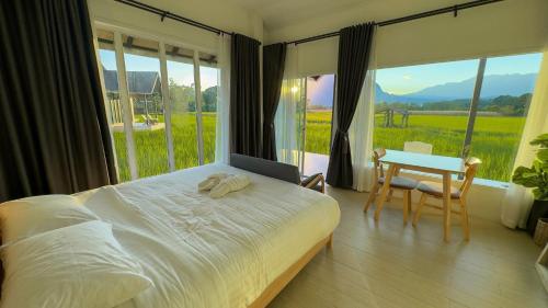 a bedroom with a bed and a table with a view at บ้านผ่อดอยกอยดาวพรีเมี่ยม in Ban Sop Nong