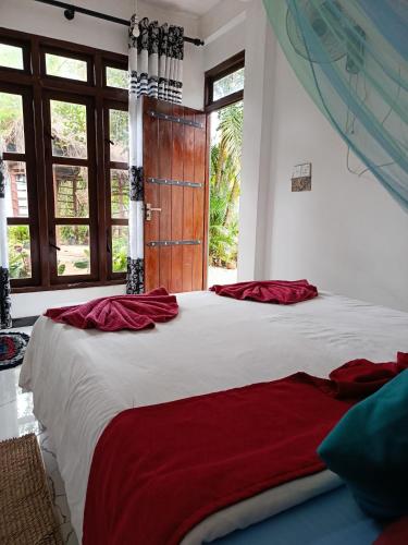 a bedroom with a large bed with red sheets at Nine Arch Corner in Ella