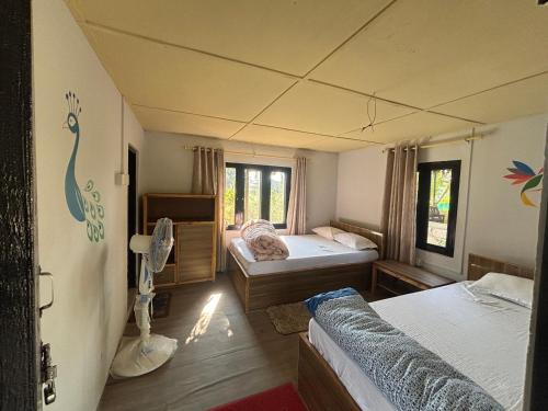 a bedroom with two beds and a room with a peacock mural at Hostel Jungle Beats in Sauraha