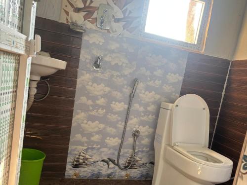 a bathroom with a toilet with clouds painted on the wall at Hostel Jungle Beats in Sauraha