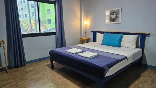 a bedroom with a bed with two towels on it at Blueplace บลูเพลส in Ban Talat Rangsit