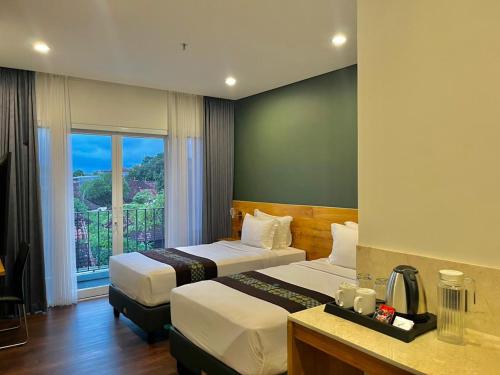 a hotel room with two beds and a window at Griya Pastoral in Denpasar