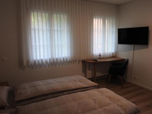 a bedroom with a bed and a desk and a television at Landhotel Hirschen in Trüllikon
