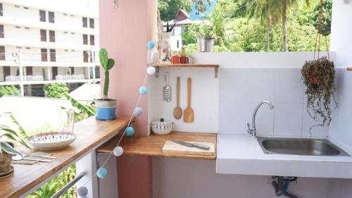 a kitchen with a counter with a sink and a window at The Grove Guesthouse in Patong Beach