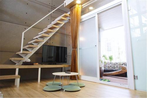 a living room with a staircase and a television at Chung Fu Inn in Tainan