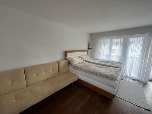 a bed and a couch in a room with a window at Satin Home in Savognin