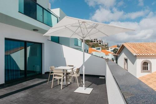 a patio with a table and a white umbrella at Vilas Mediterrâneo in Santa Cruz
