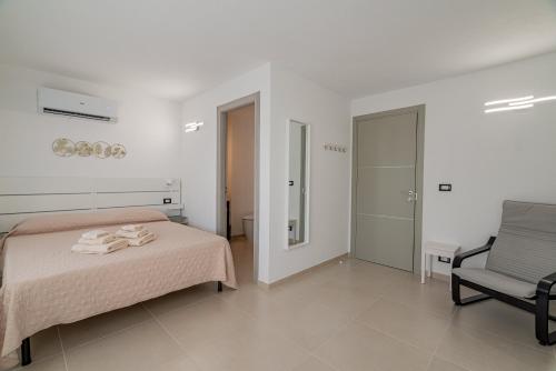 a white bedroom with a bed and a chair at Domo Le Mura Puniche, nel cuore di Olbia in Olbia