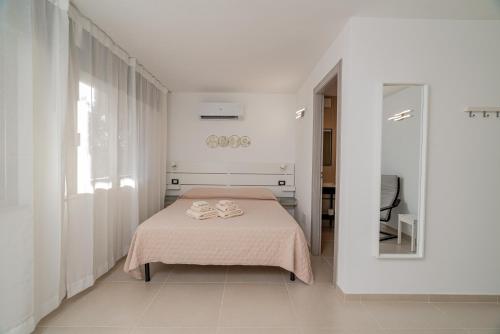 a white bedroom with a bed and a mirror at Domo Le Mura Puniche, nel cuore di Olbia in Olbia