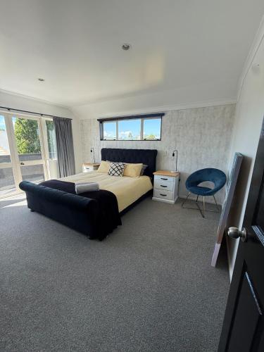 a bedroom with a large bed and a blue chair at City centred living! in Palmerston North