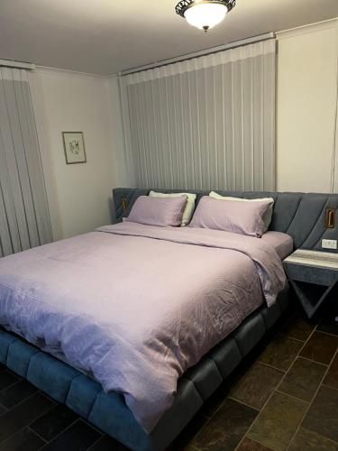 a large bed with purple sheets and pillows on it at Bicheno getaway for two in Bicheno