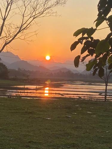 a sunset over a body of water with the sun setting at Palafita Bungalow in Phong Nha