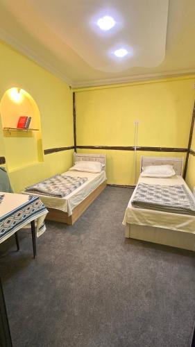 two beds in a room with yellow walls at Dom Hostel in Samarkand