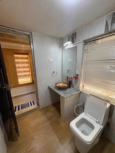 a bathroom with a white toilet and a sink at Rozana Retreats Ooty in Ooty