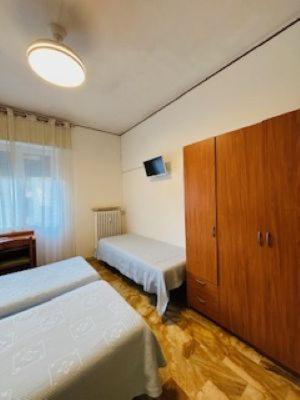 a bedroom with two beds and a wooden cabinet at Pensione Aurora in Imperia