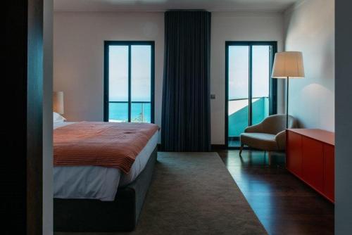 een hotelkamer met een bed, een stoel en ramen bij Vilas Mediterrâneo in Santa Cruz