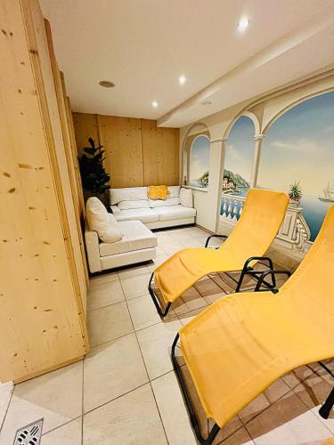 a room with yellow chairs and a balcony with the ocean at Apart Fridl in See