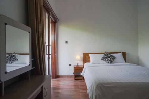 a bedroom with a bed and a flat screen tv at Rumah Kecil kesari in Denpasar