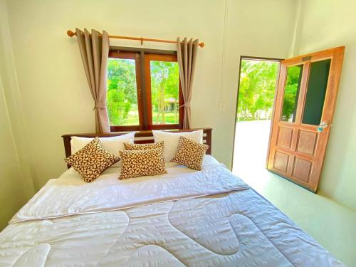 a bedroom with a bed with pillows and a window at ลียา รีสอร์ท in Ban Bang Mak (1)