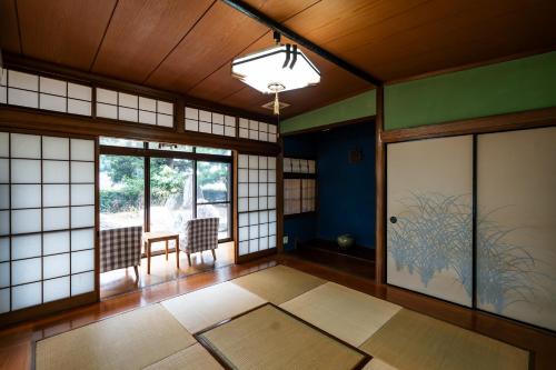 a room with a door and a table and chairs at ゲストハウス nagatafure in Iki