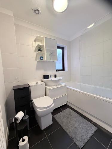 a bathroom with a toilet and a sink and a tub at Stylish 3BR Cambridge Bungalow, Near Science Park in Cambridge