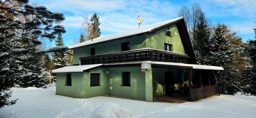 a green building in the snow with a bird on the roof at Chata Bella in Smižany