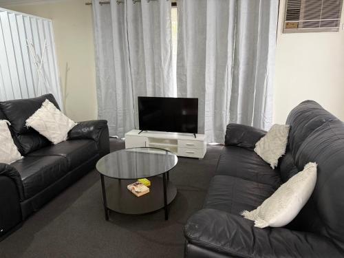 a living room with black leather furniture and a flat screen tv at Holiday Home in Drouin in Drouin
