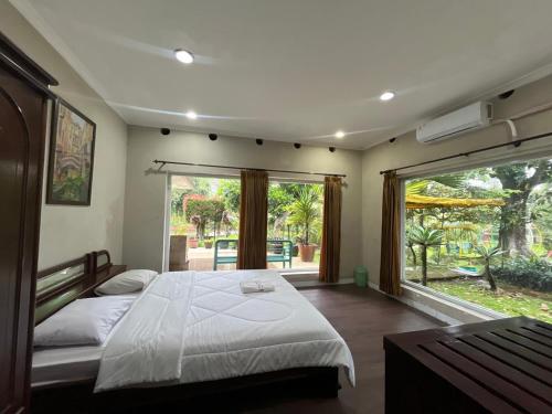 a bedroom with a large bed and a large window at Resort Botoel at Puncak in Tagalbato