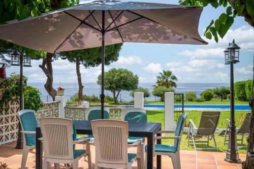 a table with chairs and an umbrella on a patio at AT084 Piscina compartida con 3 casas y vistas al mar in Torredembarra