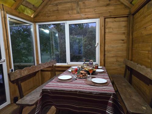 a table in a wooden cabin with a tablecloth on it at Садиба У баби Христі in Shupiki