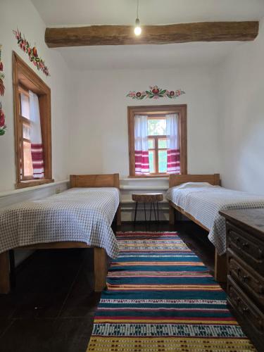 two beds in a room with two windows and a rug at Садиба У баби Христі in Shupiki