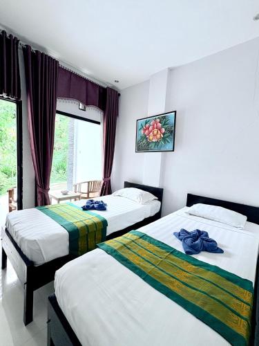 a hotel room with two beds and a window at La Colina Komodo Hotel in Labuan Bajo