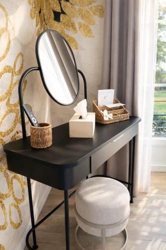 a black dressing table with a mirror and a stool at La Villa Blanche Appart hôtel in Salles