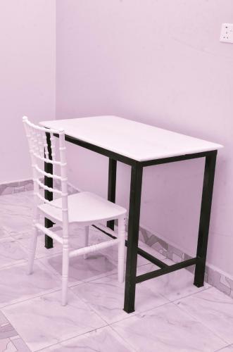 a chair sitting next to a table and a white table and a chair at Kanti Guest House, Arua in Arua