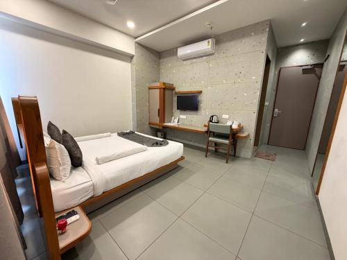 a bedroom with a bed and a desk and a television at Euphoria The Fine Dine in Surat