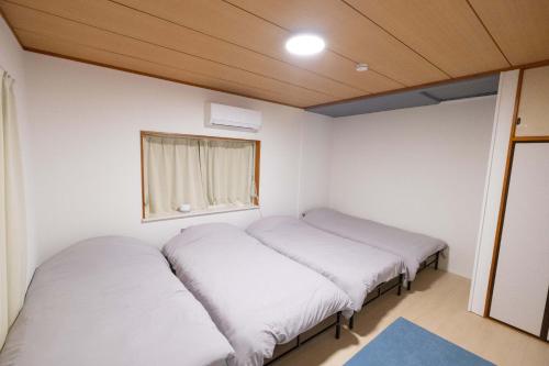two beds in a small room with a window at 里山ハウス in Kamogawa
