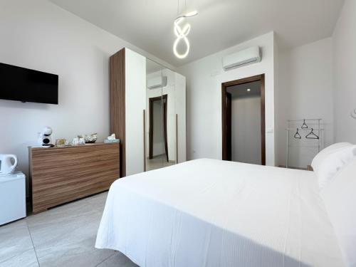 a white bedroom with a large bed and a tv at Pompei Comfort Room in SantʼAntonio Abate