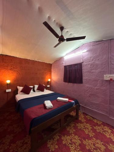 a bedroom with a bed with a ceiling fan at Prakriti Resort in Arambol