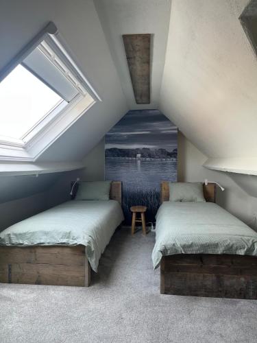 a attic room with two beds and a window at Huisje Scheldevallei in Temse
