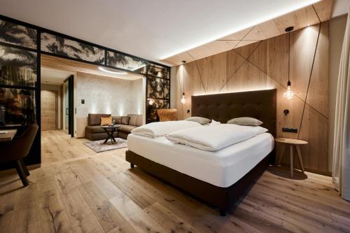a bedroom with a large bed and a living room at VALARA Alpine Art Hotel in Tux
