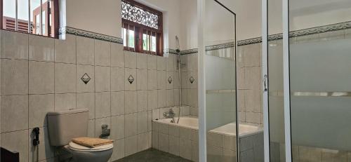 a bathroom with a shower and a toilet and a sink at Surf Villa Hikkaduwa in Hikkaduwa