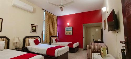 a hotel room with two beds and a red wall at Herfa INN Hotel Lahore in Lahore