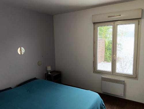 a bedroom with a blue bed and a window at Appartement rez-de-chaussée calme in Neuilly-lʼÉvêque