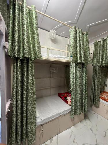 a room with two bunk beds with green curtains at Bunk House in Rishīkesh